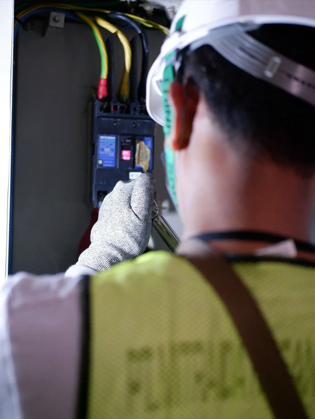 Electrician in a hard hat working on a breaker panel